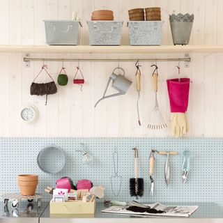 Potting station with garden tools and terracotta pots and garden string and watering can hanging on hooks