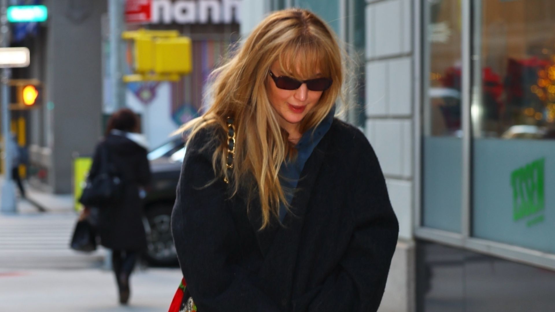 Jennifer Lawrence walks down the street in New York wearing navy felted shoes, cream trousers and a black coat.