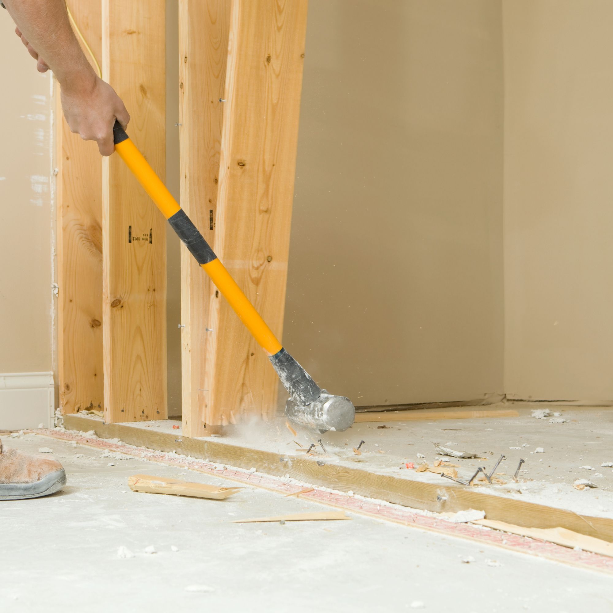 Person using a sledgehammer to knock down a non load-bearing stud wall