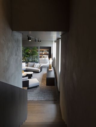 Looking down towards two rooms with large sofas and side units, divided by a green plant wall.