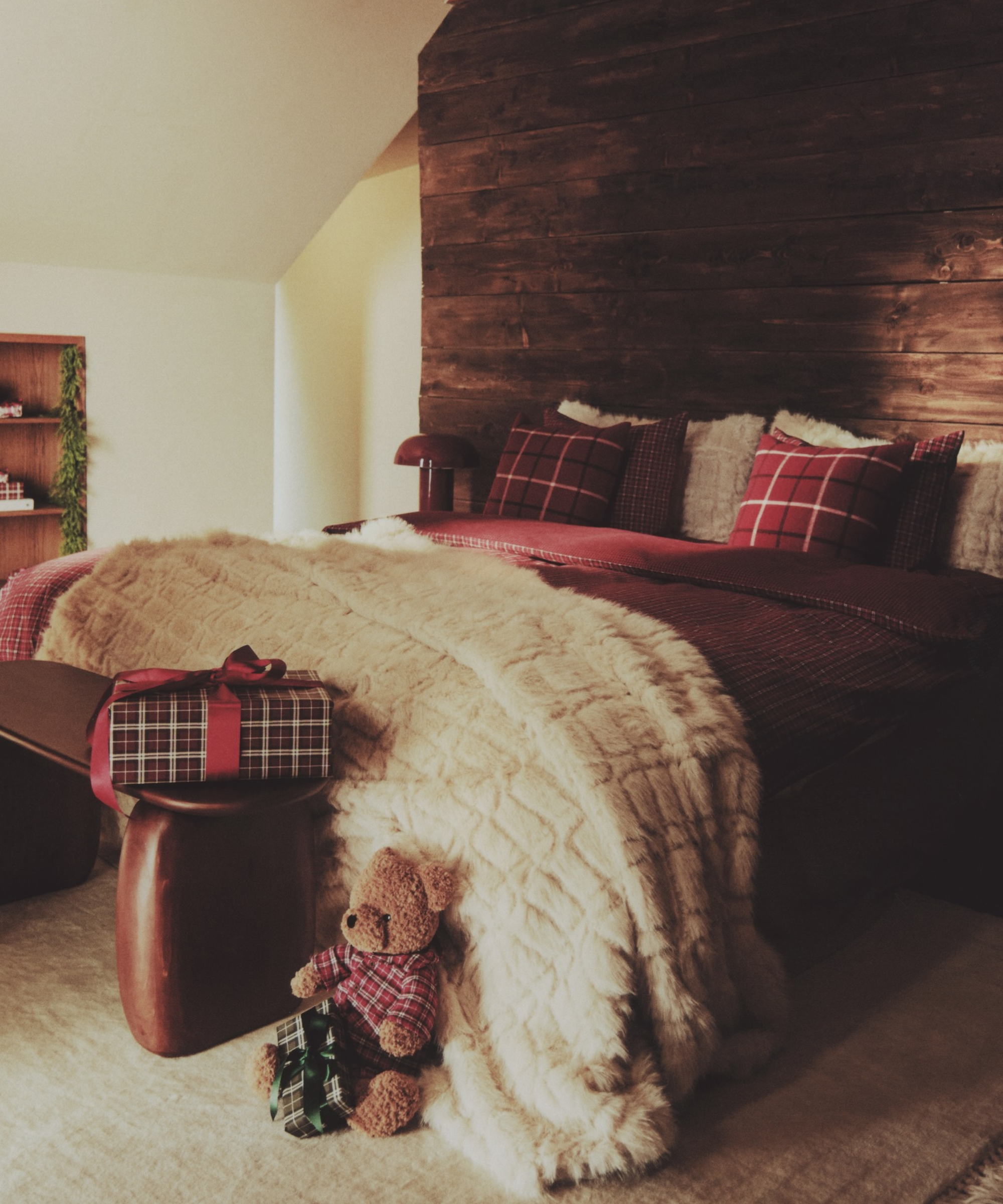 Cozy mountain cabin bedroom featuring plaid bedding, a faux fur throw blanket, and a charming stuffed teddy bear toy.