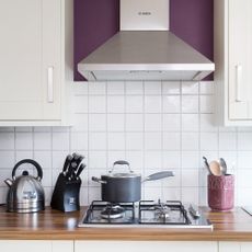 Kitchen with a stove and extractor fan and tiled backsplash