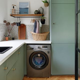 green kitchen units in utility room with washing machine
