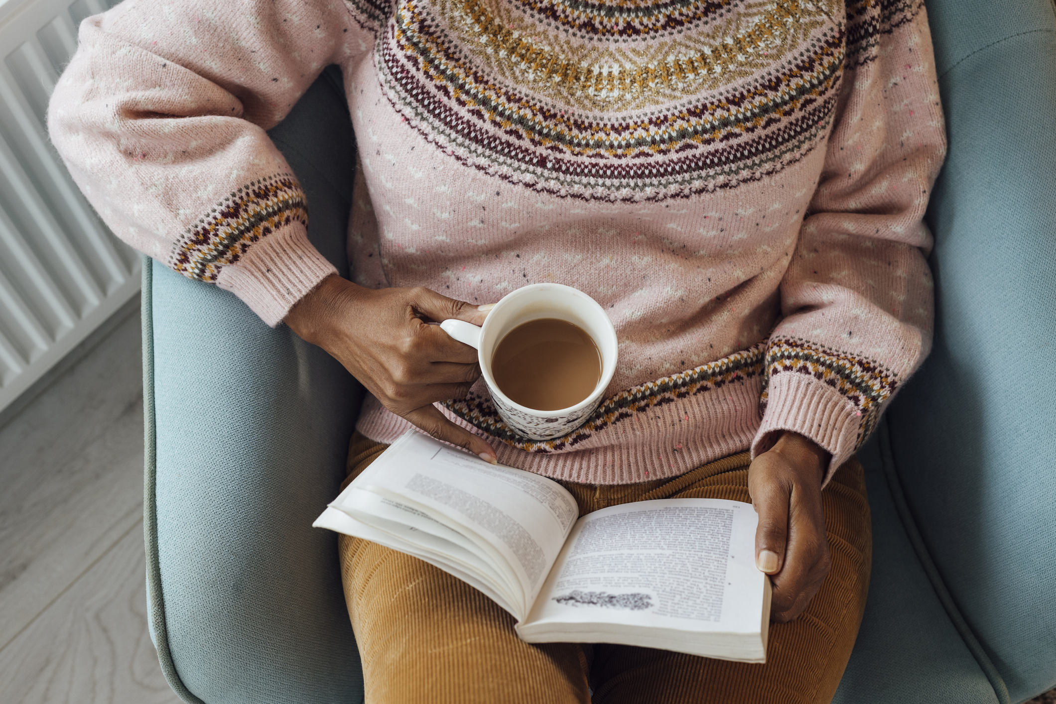 A person enjoying a book with a mug of tea.