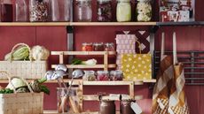 Cherry red kitchen with pale wooden shelves, wicker baskets, and glass jars