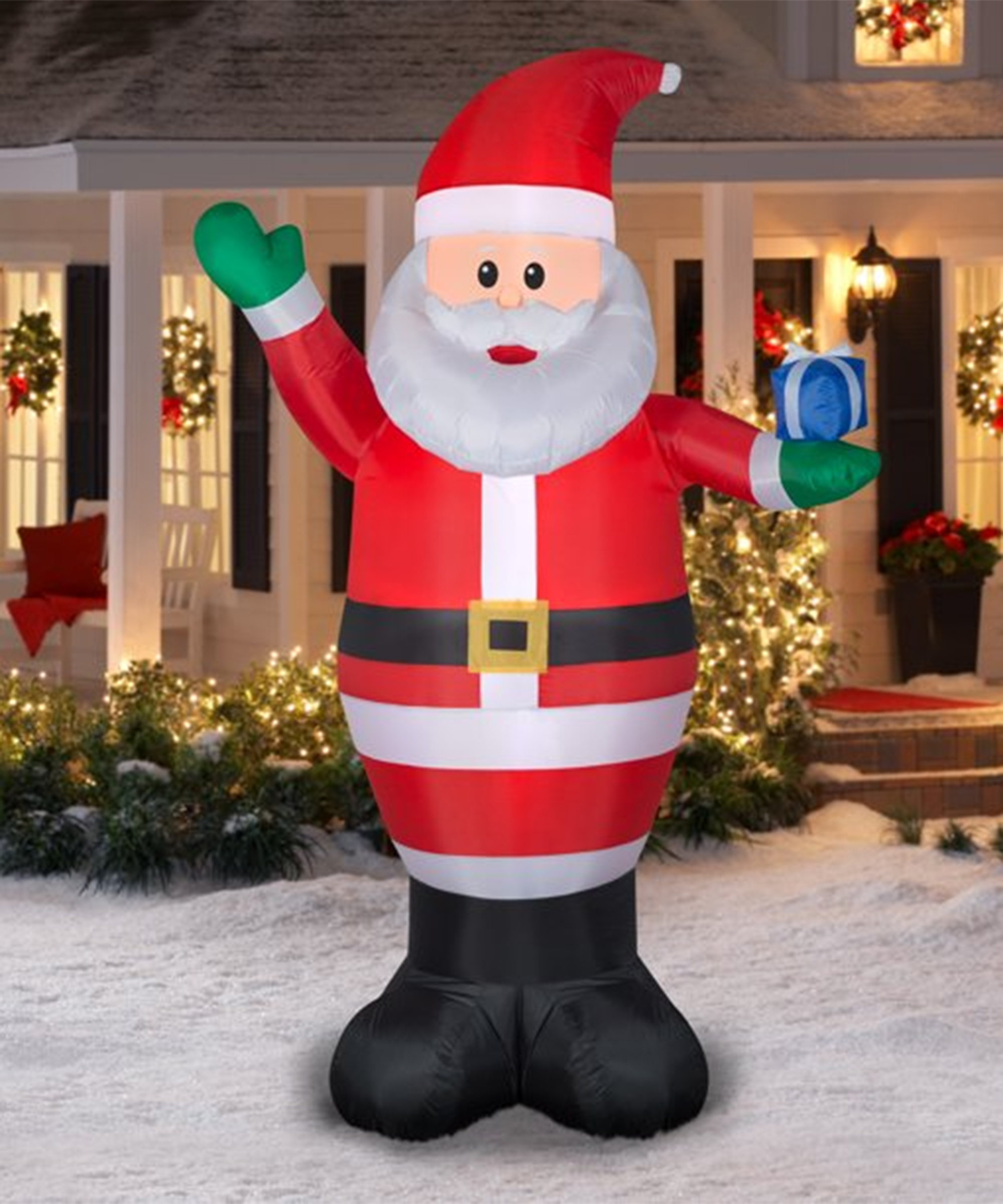 9ft airblown inflatable Santa stood outside of home which has outdoor bushes lit with fairy lights