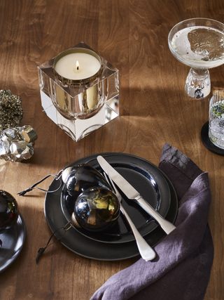 Festive table setting with black tableware, baubles and scented candle