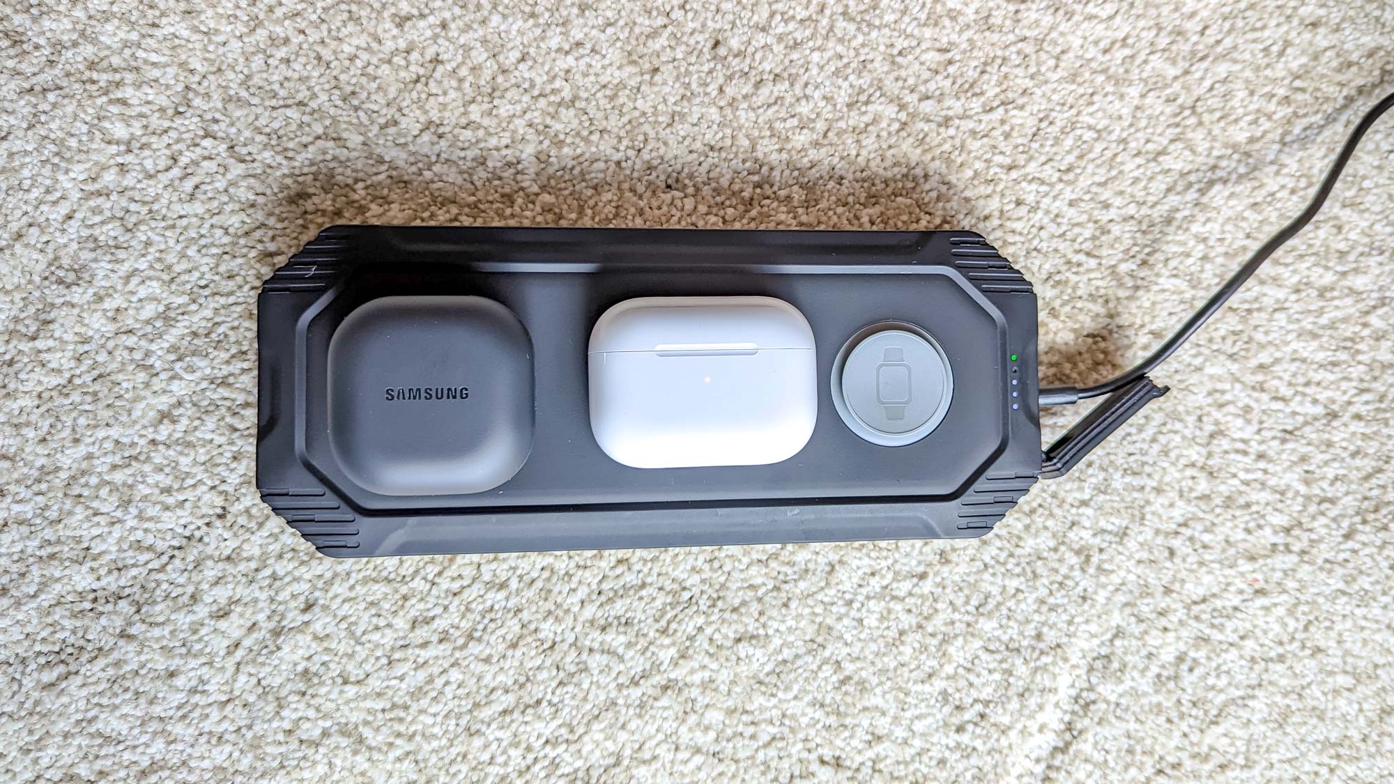 AirPods Pro 2 and Samsung Galaxy Earbuds 2 Pro side-by-side on wireless charger on a wall outside