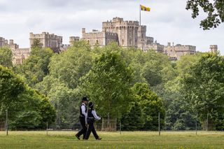 Windsor Castle exterior with two police officers walking through the park in front