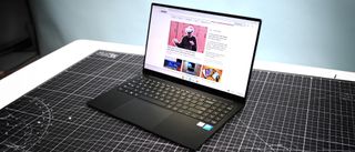 Samsung Galaxy Chromebook Plus on a black and white desk with a blue background.