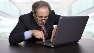 Un hombre de negocios confundido tratando de usar su portátil en la oficina