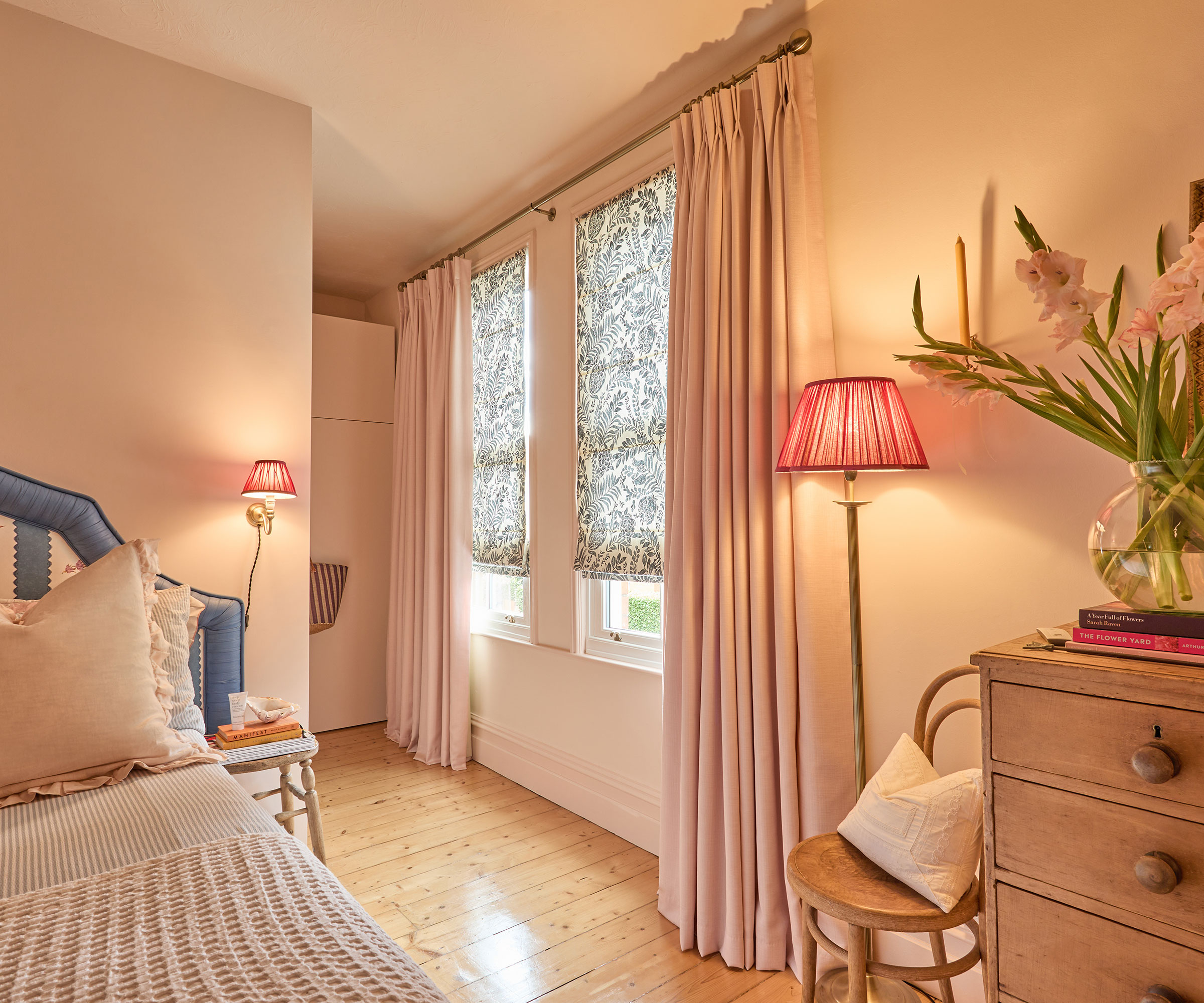 pink bedroom with floral blinds and pink floor length curtains