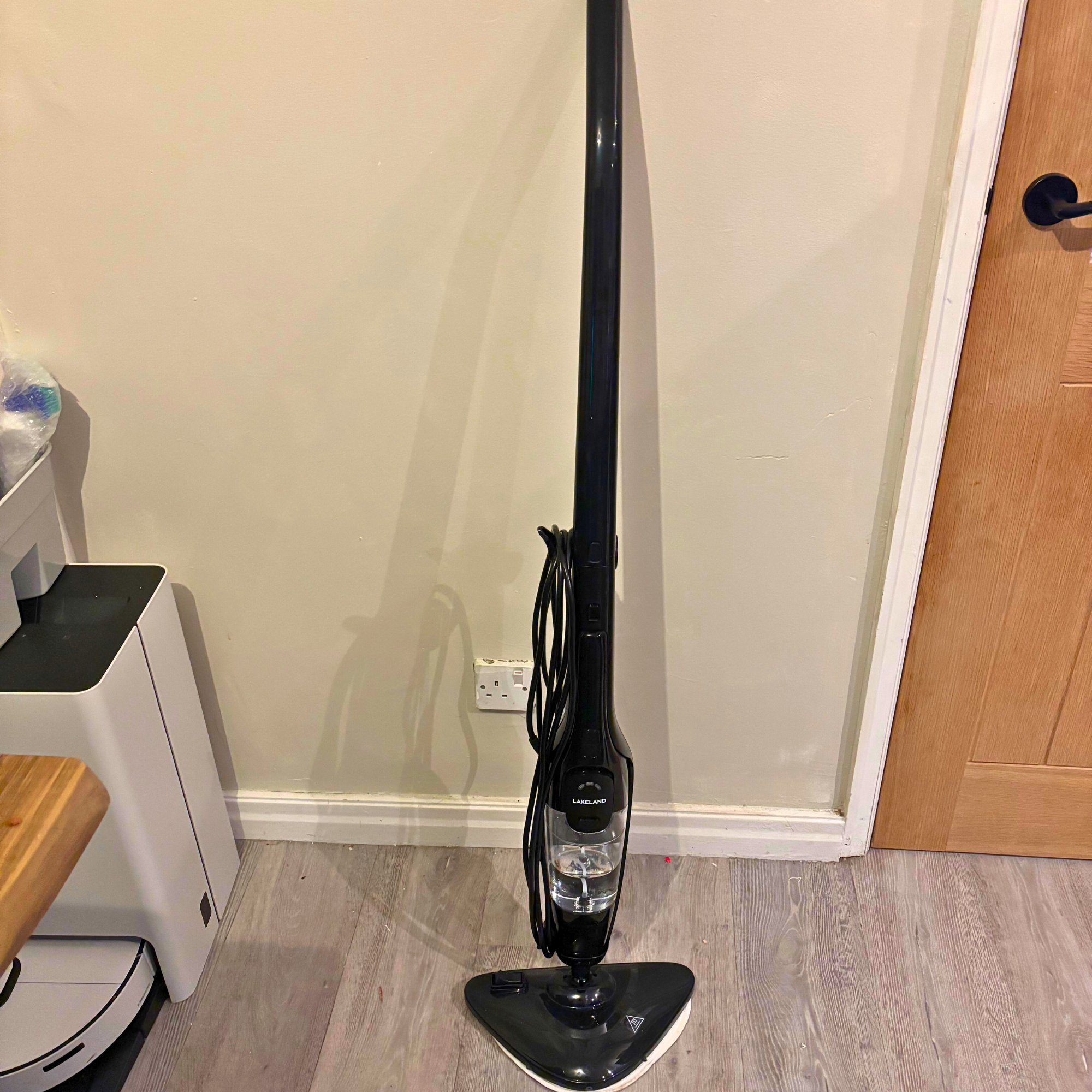 Lakeland 2-in-1 Steam Mop stood upright against kitchen wall