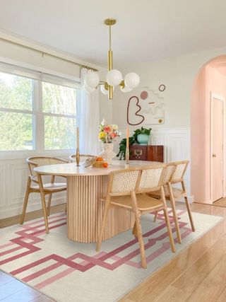 A dining room with a wooden dining set and a pink rug