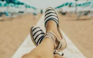 A view of a woman on a beach wearing espadrilles