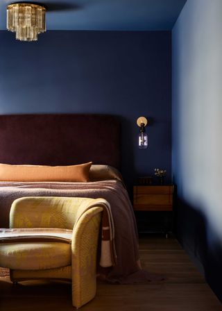 a blue bedroom with a red and orange bed