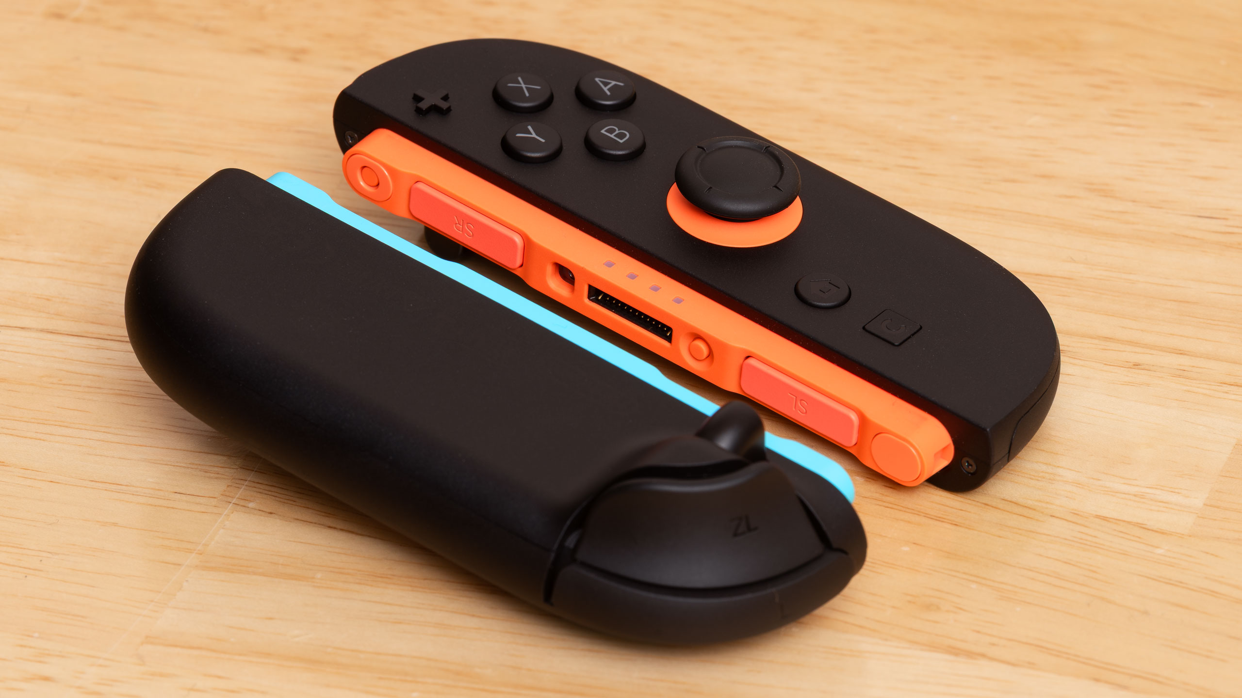 A view of the two Nintendo Switch 2 Joy-Con 2 controllers, one face-down to show the bumper and trigger, the other face-up, showing the buttons and joystick