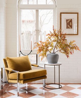 Cozy lounge chair with fall foliage in vase on side table