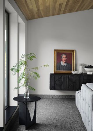 A living room with a mounted credenza and a side table with a bud vase