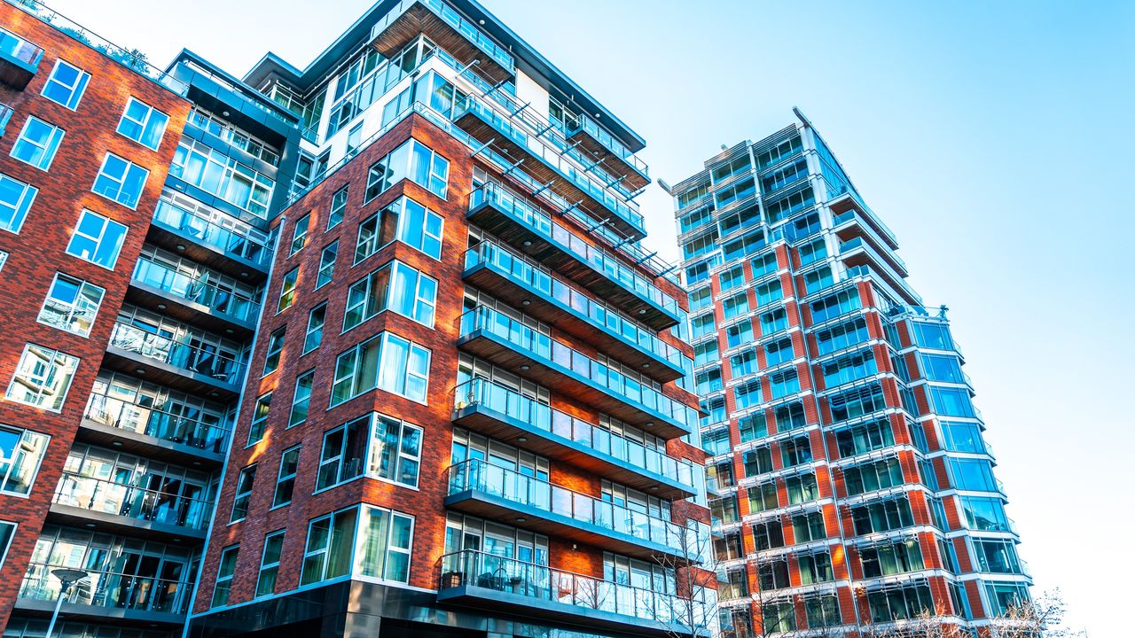 An apartment building that could be used in a 1031 exchange rises up against a blue sky.