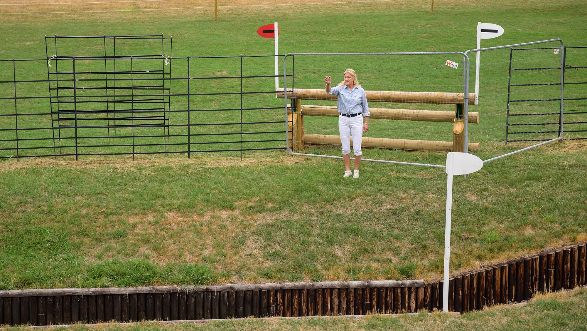 Event rider Tina Cook standing behind a triple bar fence and looking down at an open ditch, on the Burghley cross-country course 2026
