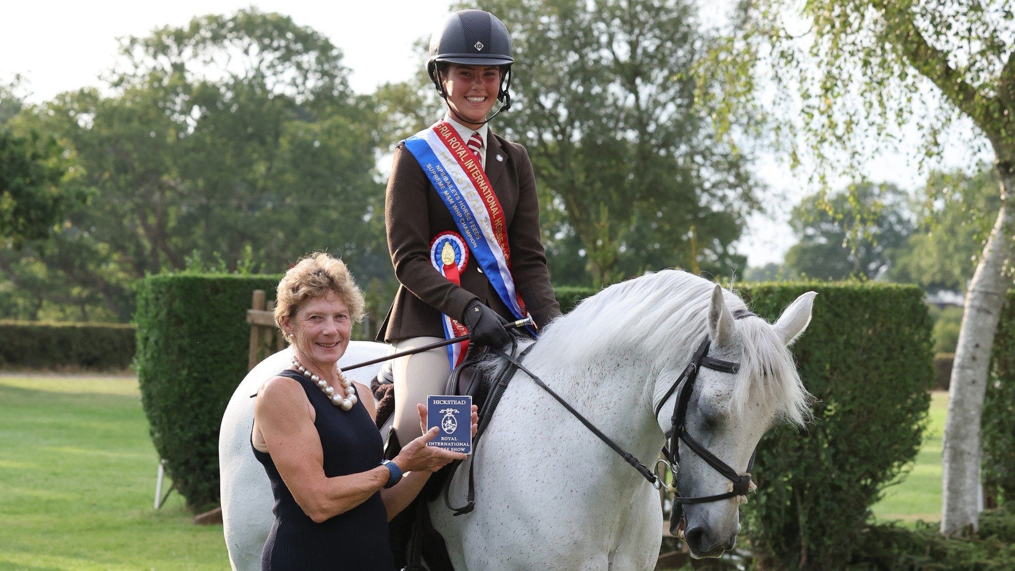 Izzie Williams wears a championship sash and sits on a standing Mayfield Boy for a photo with sponsor at the 2026 RIHS 