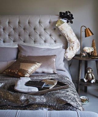 A grey and taupe Christmas-themed bedroom with metallic decor and sequin homewares with chesterfield style button headboard