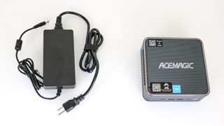 The Acemagic F2A mini PC next to its power adapter