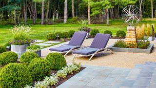 A backyard lounge chairs, bright green plants and mulch