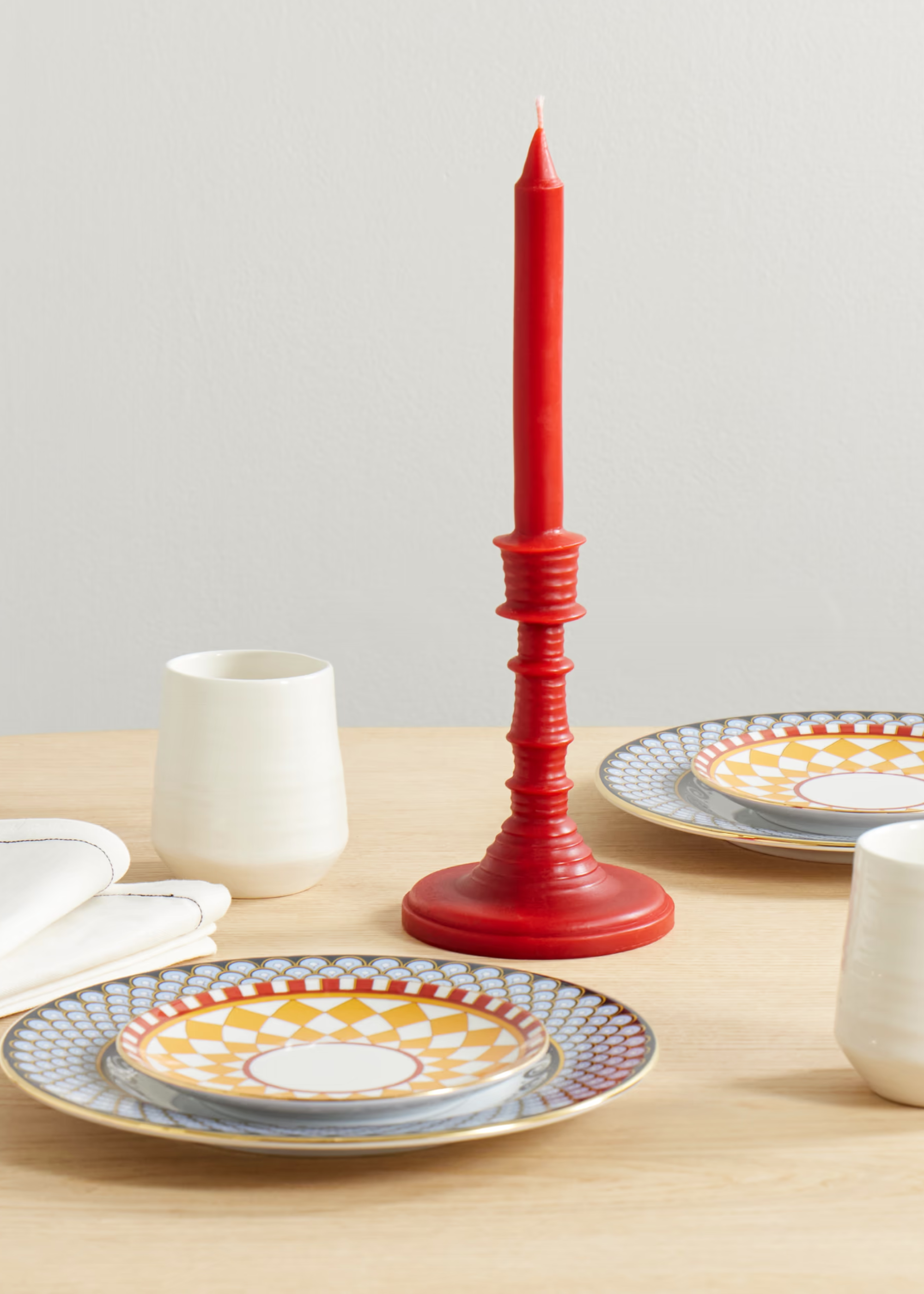 A tomato scented candlestick on a set table with colorful plates