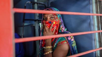 a migrant worker looks out of a compartments window as she sits inside a special train going to agra in uttar pradesh state during a government imposed nationwide lockdown as a preventive measure against the covid 19 coronavirus, at sabarmati railway station on the outskirts of ahmedabad on may 2, 2020 photo by sam panthaky afp photo by sam panthakyafp via getty images