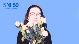 Riley Utley on a blue background holding up flowers to her face.