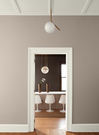 entrance way through to dining room, earthy paint tones, globe pendant light, wooden floor, modern white dining chairs