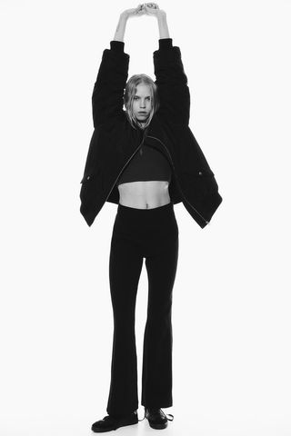 model wears Flared Leggings, black crop top, and black zipped hoodie