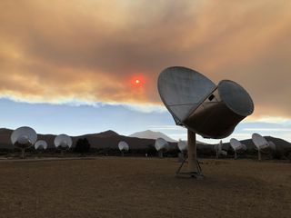 A view of the Allen Telescope Array shows antennas under a smoke-filled sky and a red-tinged sun on Sept. 7, 2021.