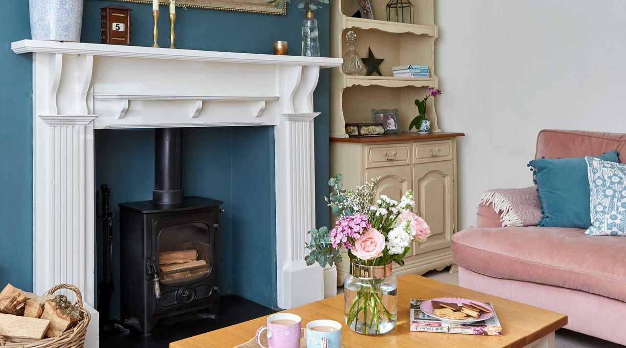 living room fireplace with white mantel against dark blue wall and dresser in alcove