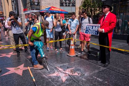 A work crew digs up the vandalized Donald Trump star