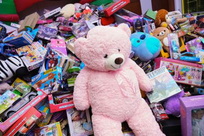 A large pink stuffed bear on top of a pile of toys