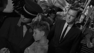 A man in a uniform carries an injured boy in The Twilight Zone episode Walking Distance