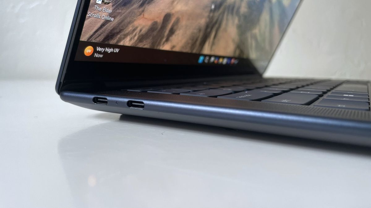 Close up of connectivity ports on the side of a black laptop on top of a white surface.