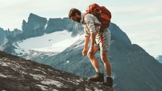 Tired man hiking up mountain