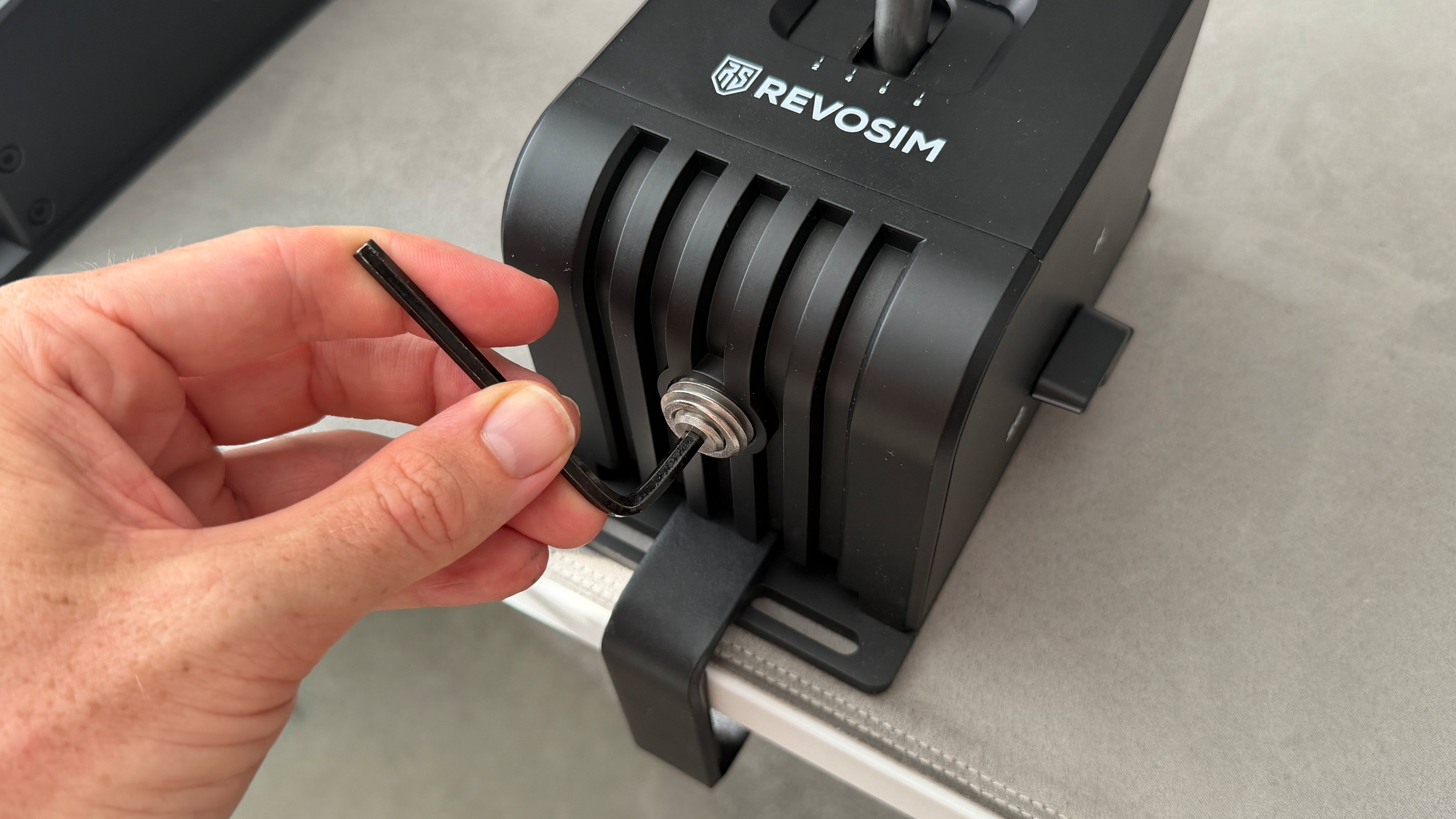 A reviewer tightening down the desk clamp on the Revosim gear shifter
