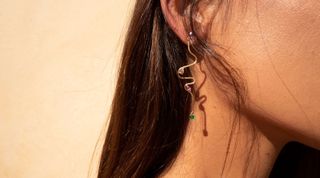 Woman wearing gold curving earring with gems on