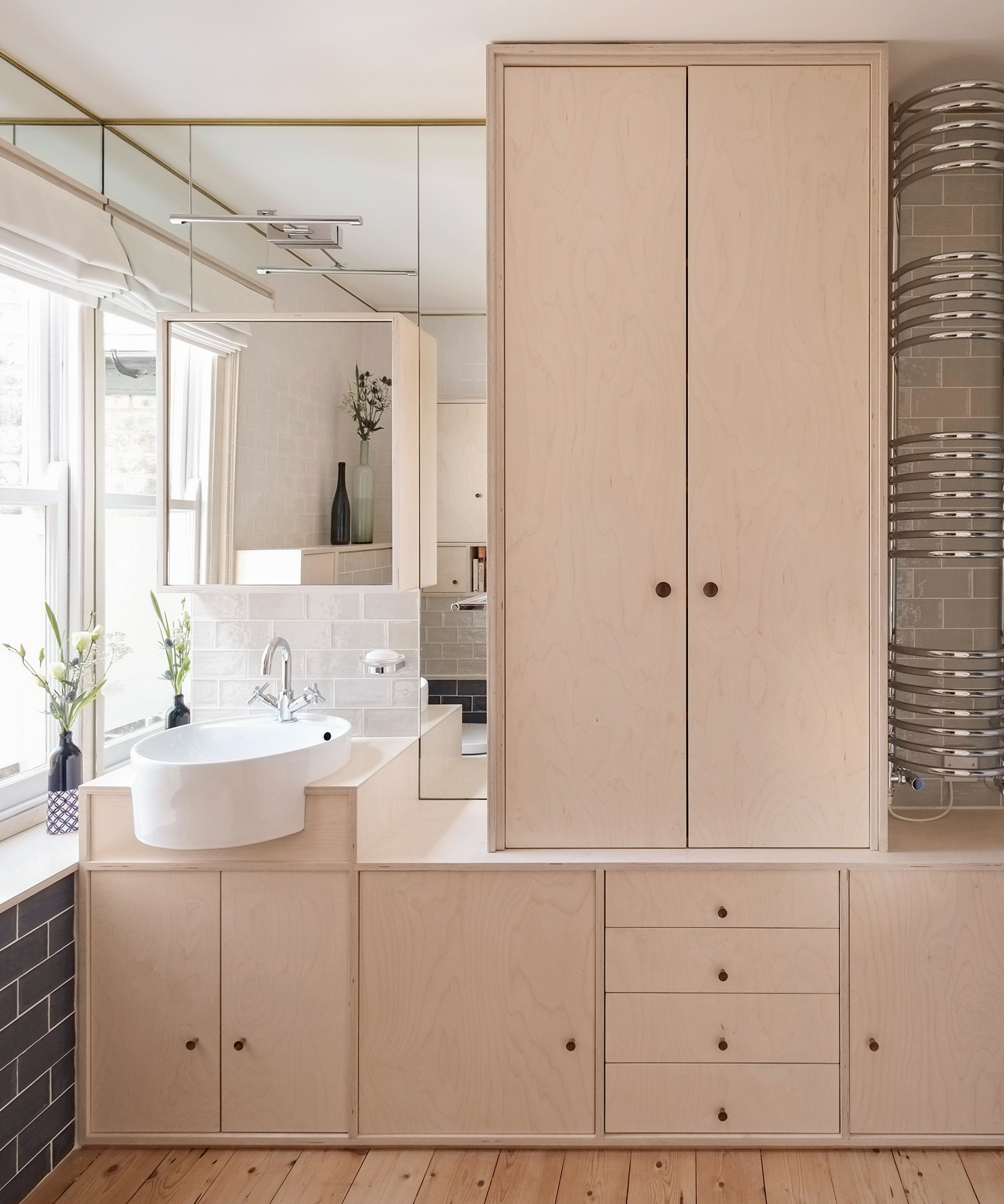 A bathroom sink set in a bespoke birch plywood storage with drawers and cupboards
