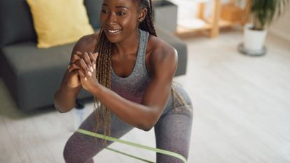 Woman performs banded squats with a resistance band around her thighs