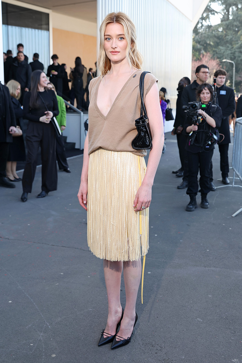 Sarah Pidgeon attending the Prada F/W 26 show during MFW wearing a an oatmeal-colored V-neck tank top and fringed butter yellow skirt with black pumps