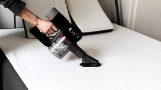 person using vacuum to clean a mattress