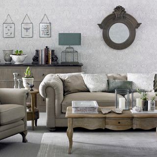 living room with patterned wallpaper and grey sofa with cushions