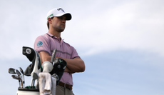 Thomas Detry stands by his golf bag and watches on