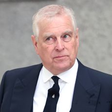 Prince Andrew wears a black suit and matching tie with a white shirt and looks to the sky in a bemused quizzical way